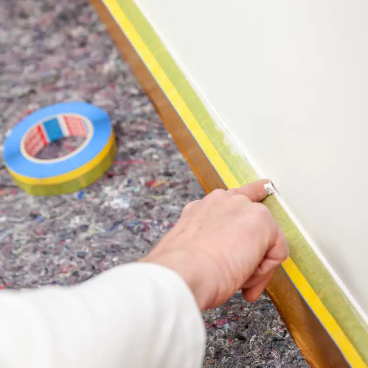 Zbliżenie na żółtą taśmę Tesa Washi UV 2w1 przyklejoną wzdłuż listwy przypodłogowej