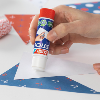 Osoba aplikuje klej Tesa Stick na biały papier podczas tworzenia kolorowej pracy plastycznej