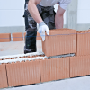 Układanie pustaka ceramicznego na warstwie pianokleju Tytan Professional podczas wznoszenia ściany
