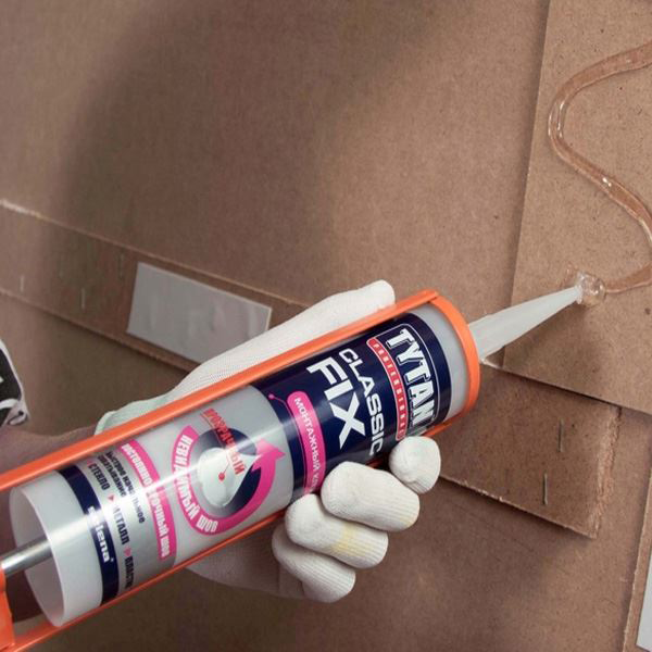 Aplikacja bezbarwnego kleju Tytan Classic Fix na płytę drewnianą podczas montażu ściany