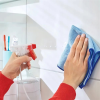Przed przyklejeniem haczyka Tesa Powerstrips osoba czyści białe płytki łazienkowe niebieską ściereczką