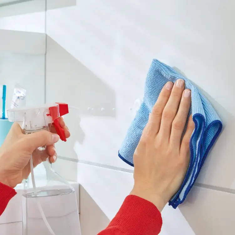 Czyszczenie płytek przed montażem haczyka Tesa Powerstrips przy użyciu niebieskiej ściereczki