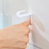 Kciuk dociska biały haczyk Tesa Powerstrips do gładkiej łazienkowej płytki ściennej