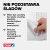 Zbliżenie na palce odklejające pasek montażowy Tesa z białej powierzchni bez pozostawiania śladów