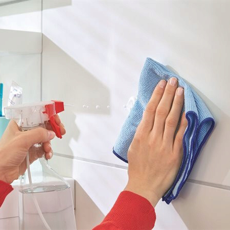 Przygotowanie powierzchni do montażu haczyka Tesa Powerstrips poprzez czyszczenie płytek wilgotną ściereczką