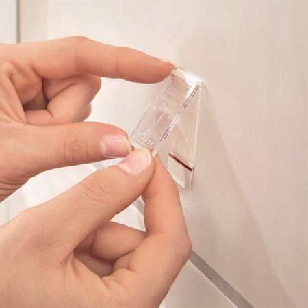Transparentny haczyk łazienkowy Tesa Powerstrips zamocowany na białej ścianie prezentuje minimalistyczny wygląd