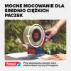 Aplikator z bezbarwną taśmą pakową Tesa zabezpiecza średniej wielkości karton na stole ogrodowym