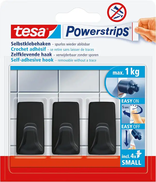 Czarne haczyki Tesa Powerstrips zamocowane na białych płytkach prezentują minimalistyczny styl w łazience