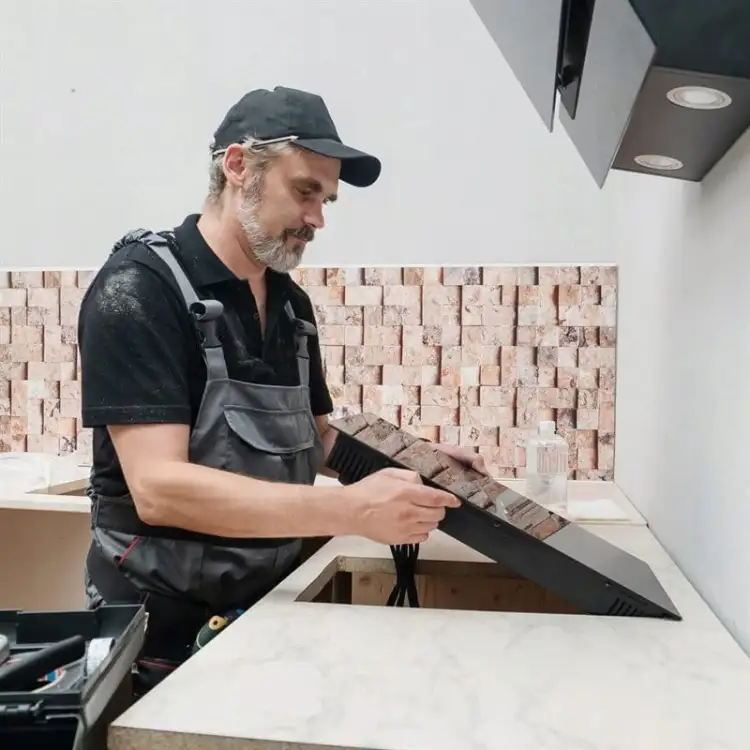 Mężczyzna przygotowuje kuchenną płytę grzewczą do montażu z użyciem taśmy piankowej Tesa