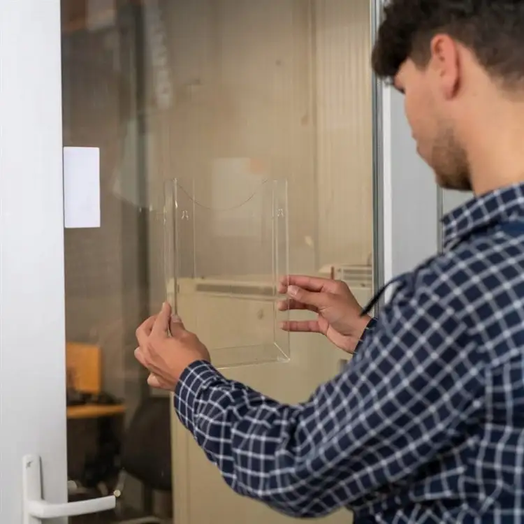 Przezroczysta taśma montażowa Tesa przytrzymuje osłonę na szklanych drzwiach biurowych dla dyskretnego efektu