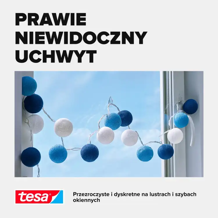Girlanda z kolorowych pomponów zawieszona na przezroczystych haczykach samoprzylepnych Tesa na oknie