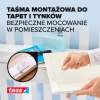 Widoczna aplikacja piankowej taśmy Tesa na ścianie podczas montażu dekoracyjnej ramki w pokoju