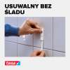 Dłoń usuwa pasek montażowy Tesa z gładkiej powierzchni płytek bez pozostawiania śladów