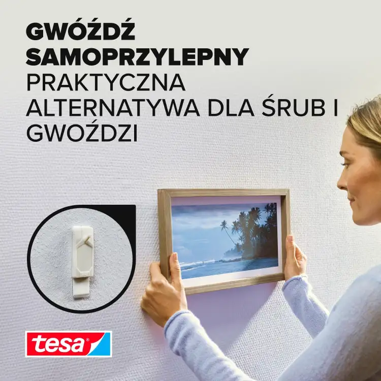 Kobieta zawiesza ramkę na ścianie przy pomocy samoprzylepnego gwoździa Tesa do tapet
