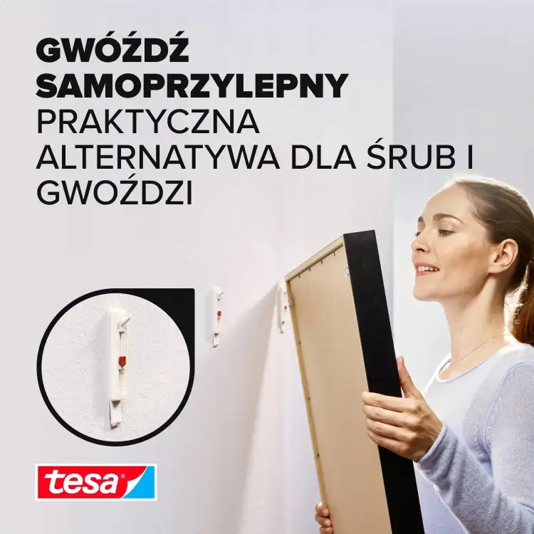 Kobieta montuje obraz na ścianie przy pomocy samoprzylepnego gwoździa Tesa do tapet