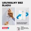 Dłoń mocuje samoprzylepny gwóźdź Tesa na ścianie pokrytej tapetą bez użycia narzędzi