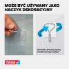 Przezroczysty haczyk Tesa zamocowany na gładkiej ścianie służy jako uchwyt na dekoracje