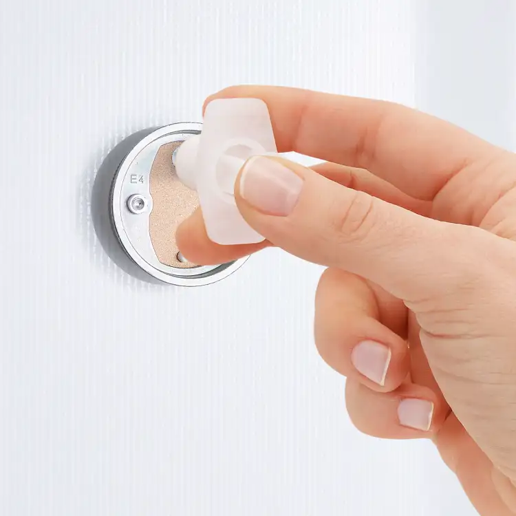Palce zdejmują plastikowy element zabezpieczający z mocowania metalowej mydelniczki Tesa LOXX przed instalacją