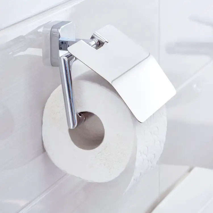 Chromowany uchwyt Tesa ELEGAANT z rolką papieru zamontowany na białych płytkach łazienkowych