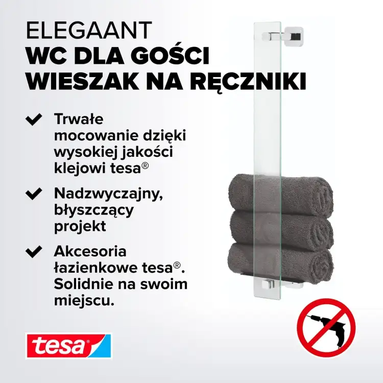 Na zdjęciu metalowy wieszak Tesa Elegaant z trzema ciemnymi ręcznikami zawieszonymi na ścianie łazienki