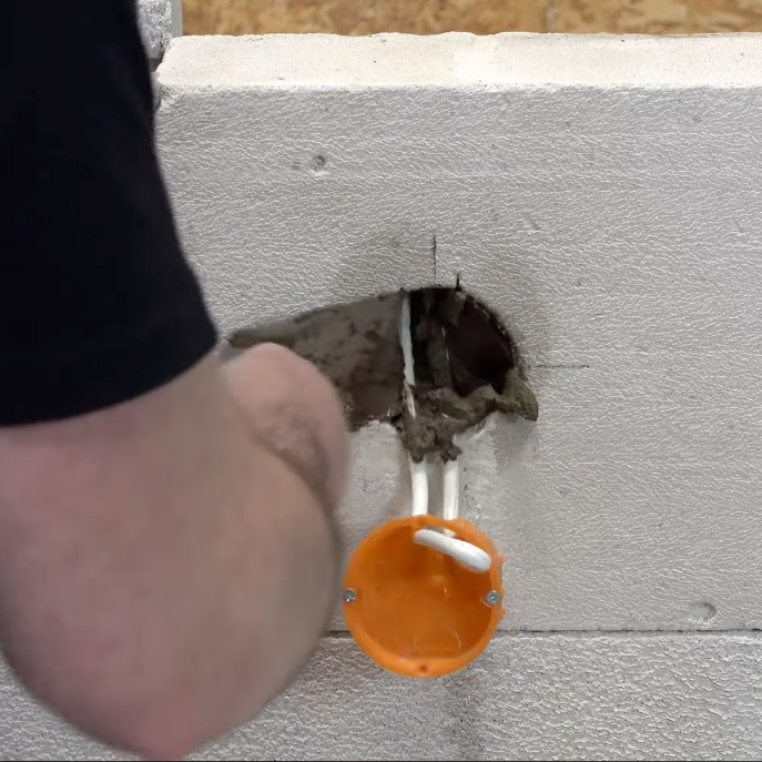 Aplikacja zaprawy cementowej Ceresit CX20 wokół puszki instalacyjnej zamontowanej w ścianie z bloczków